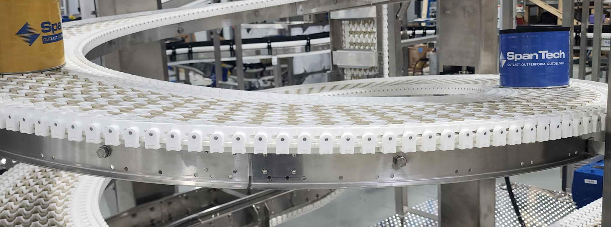 Close-up view of SpanTech plastic-chain spiral conveyor curve moving products smoothly around a tight 360° turn in a food-grade packaging line.