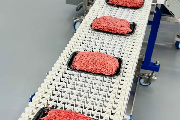 Packaged ground meat on a conveyor system. 