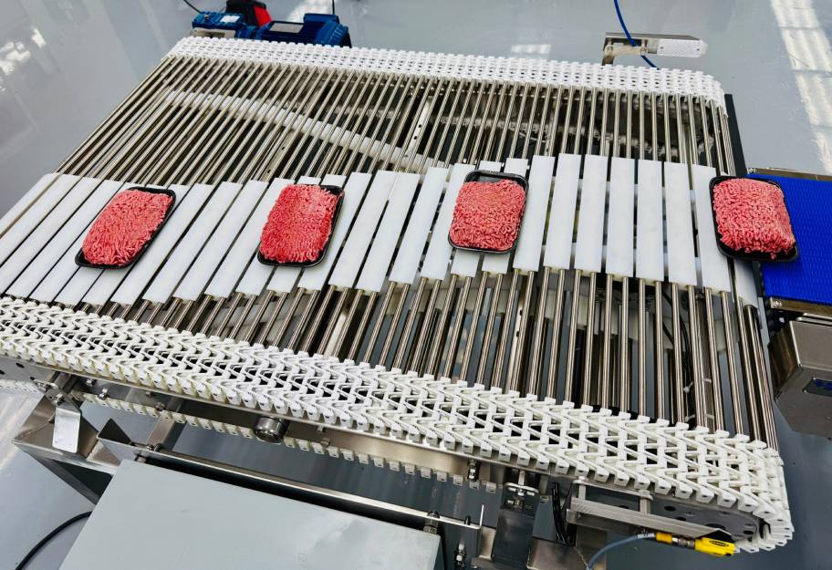 Packaged meat moving down a conveyor belt. 