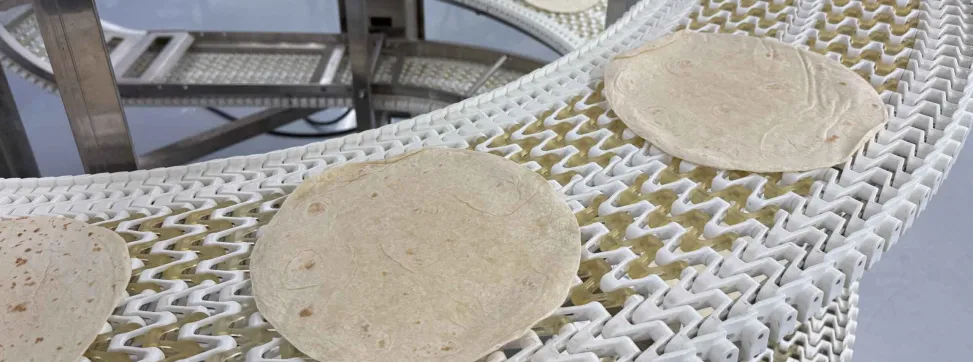 Tortillas on a conveyor belt in a manufacturing facility.