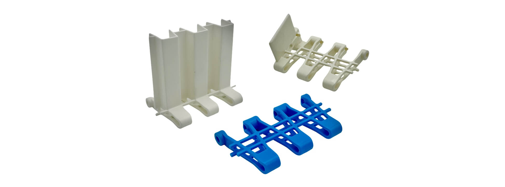 cooling-conveyor-systems-for-food-production Three modular plastic conveyor chain segments in white and blue, showing cleated and open-link designs